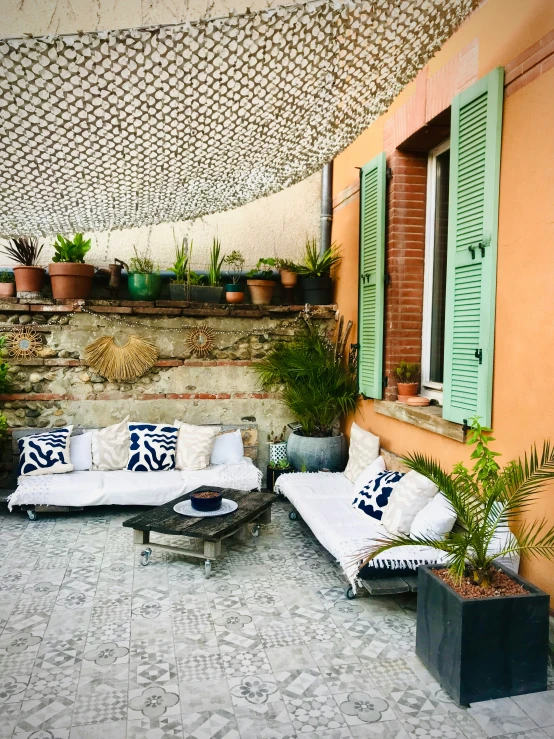 a patio with many plants and couches outside