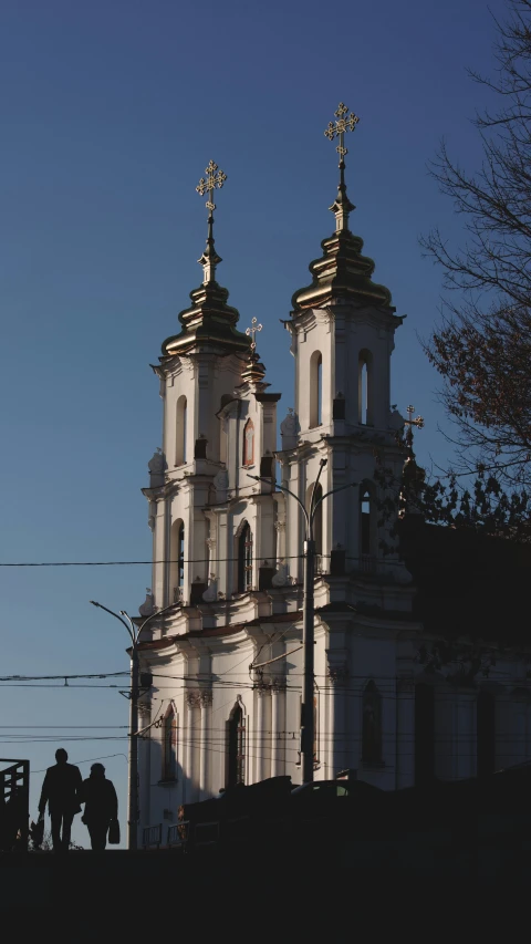 the silhouettes of people standing outside a church tower