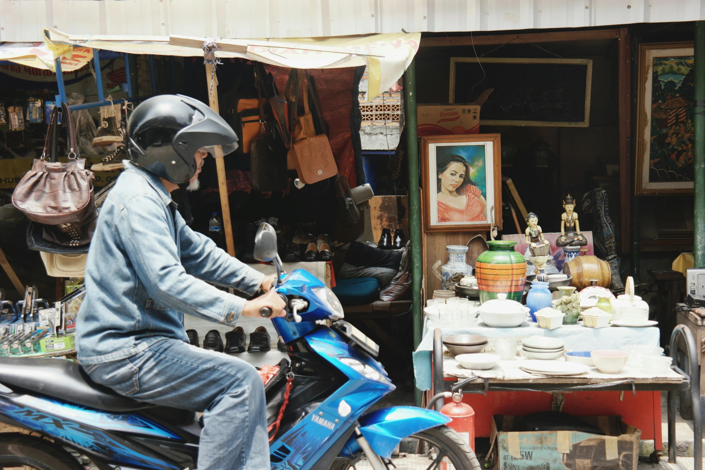 a man sitting on a blue motorcycle next to a table