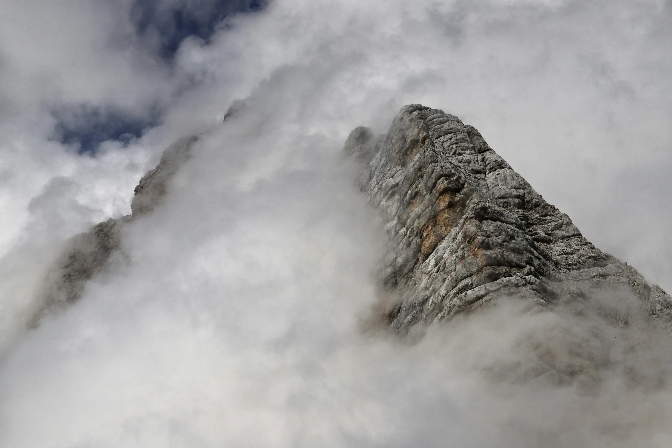 a tall mountains covered in clouds and snow