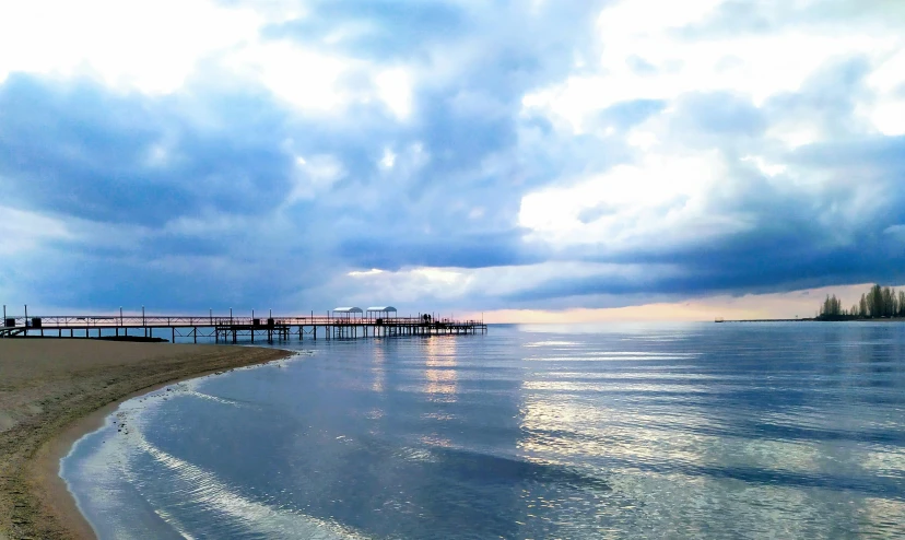 a long dock on the beach during a stormy day