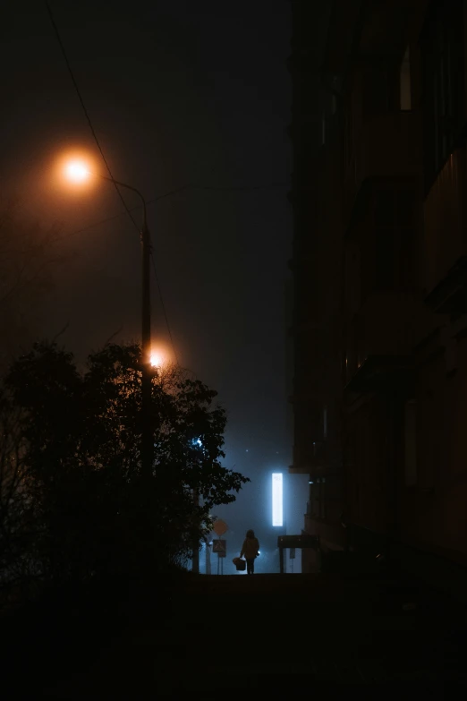 a building is lit by two lights and a person standing under the street lamp