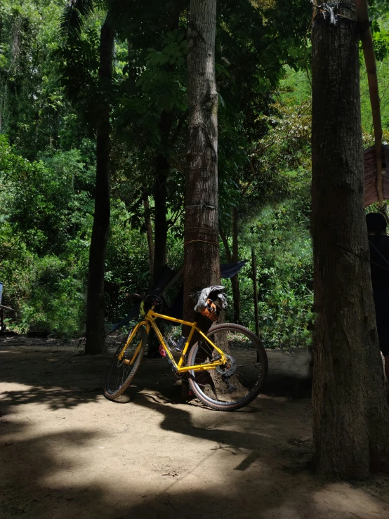 a yellow bike sitting in the shade of trees