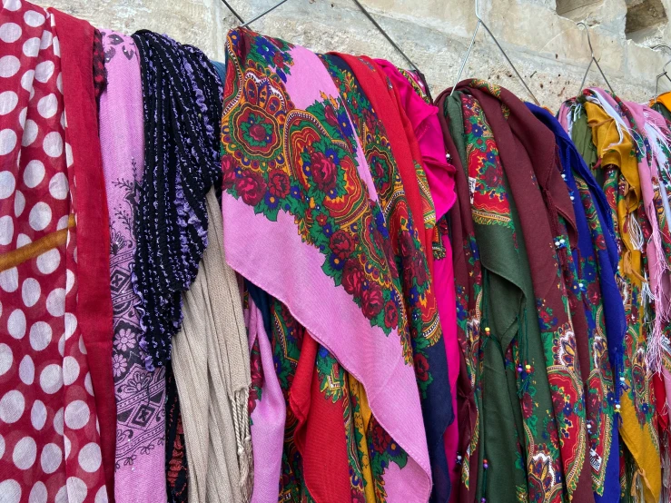 a wall covered in lots of scarves next to a building