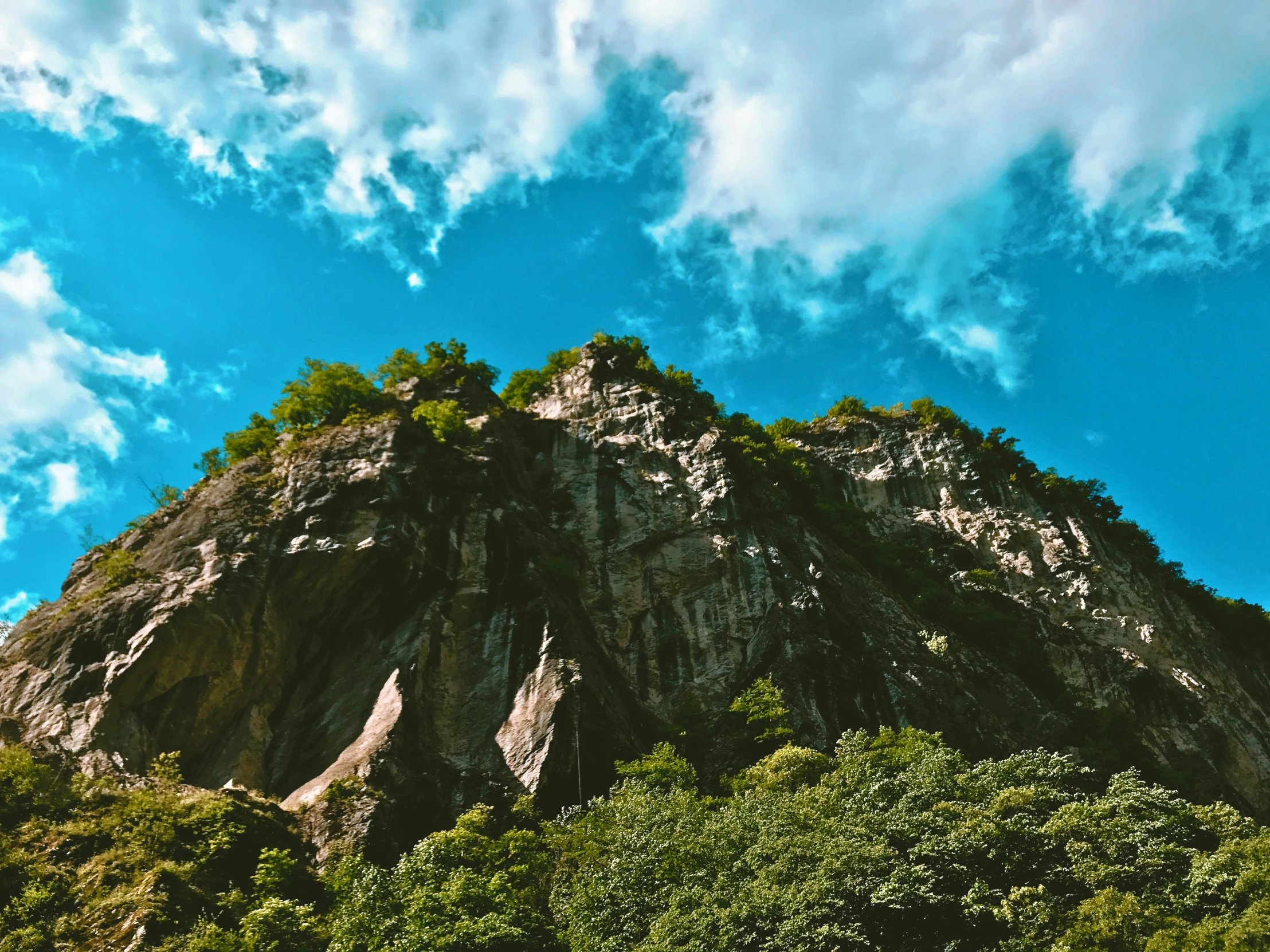 looking up at a mountain, with clouds in the sky