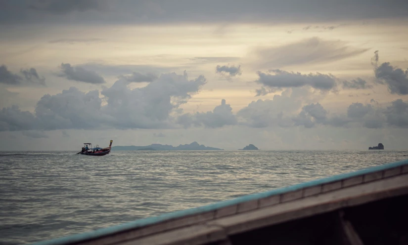 a boat traveling on the ocean under cloudy skies