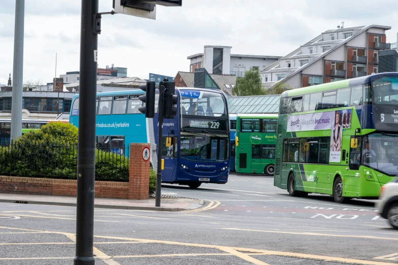 four green double decker buses in parking lot next to buildings