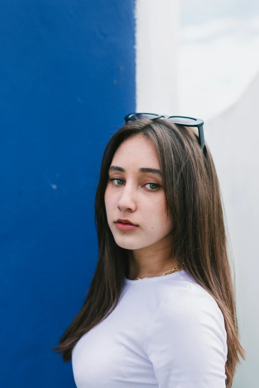 a girl wearing a pair of glasses and standing near a wall