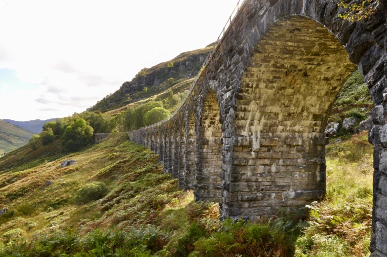 an ancient brick bridge with mountains in the background