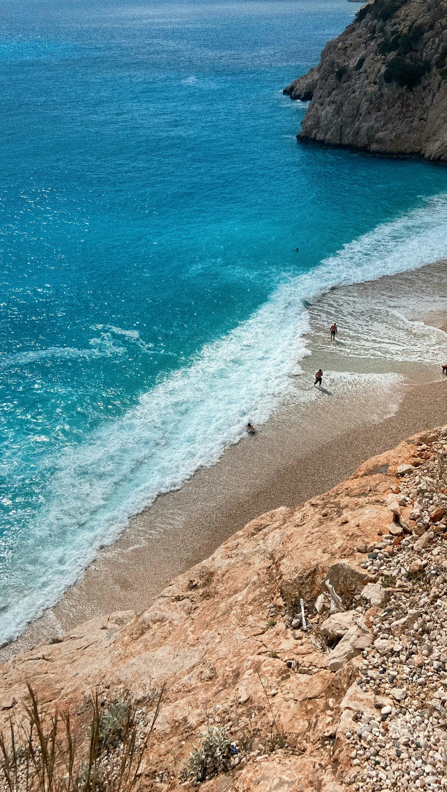 a person sitting on top of a sandy hill near the ocean