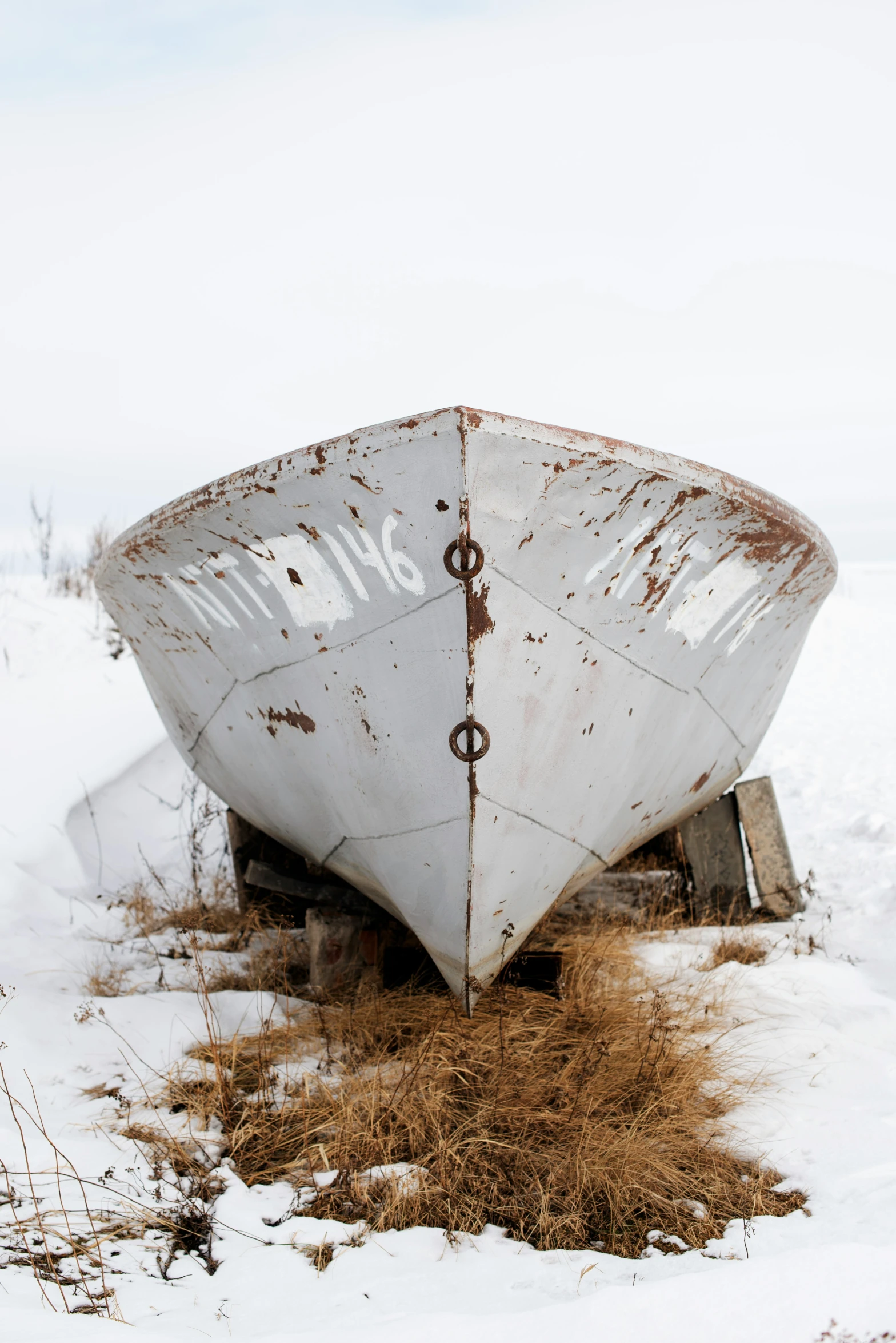 an old rusty boat in the snow on the ground