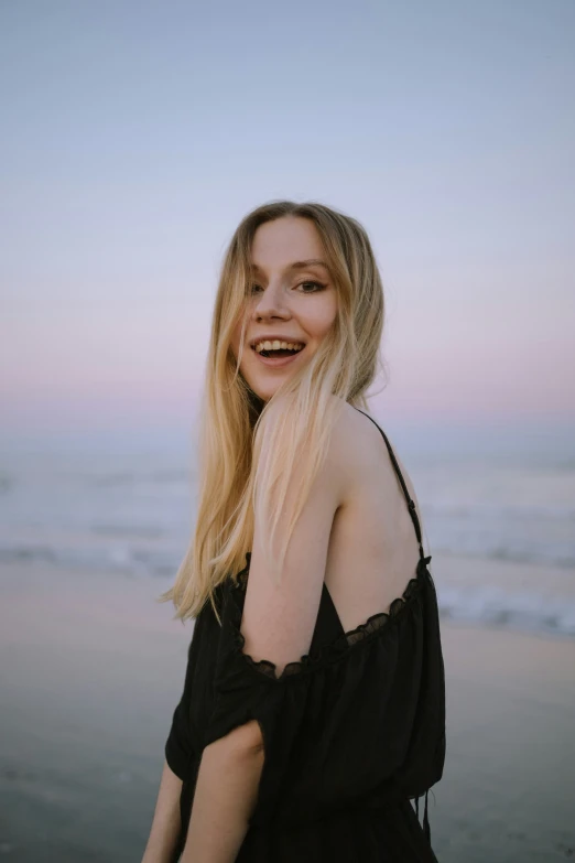 a woman smiling at the camera on a beach