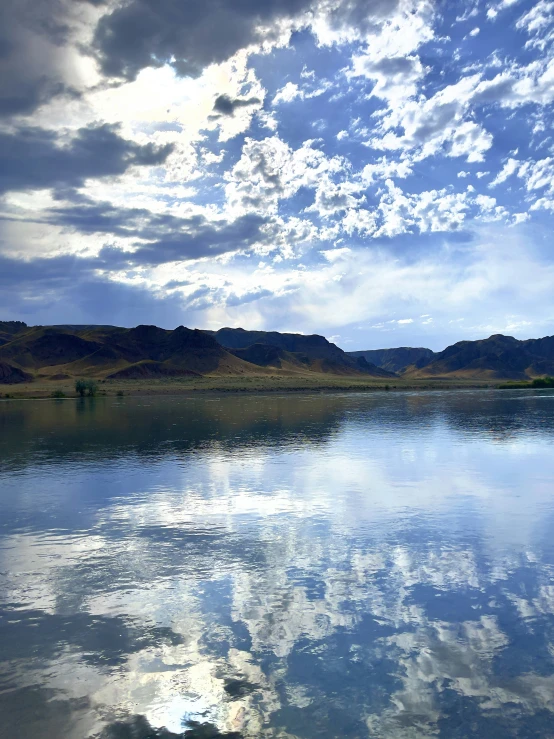 a river and the shore with sky reflecting in it