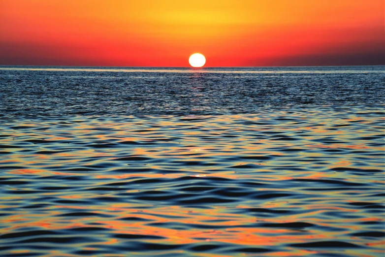 the sun setting over a body of water with waves