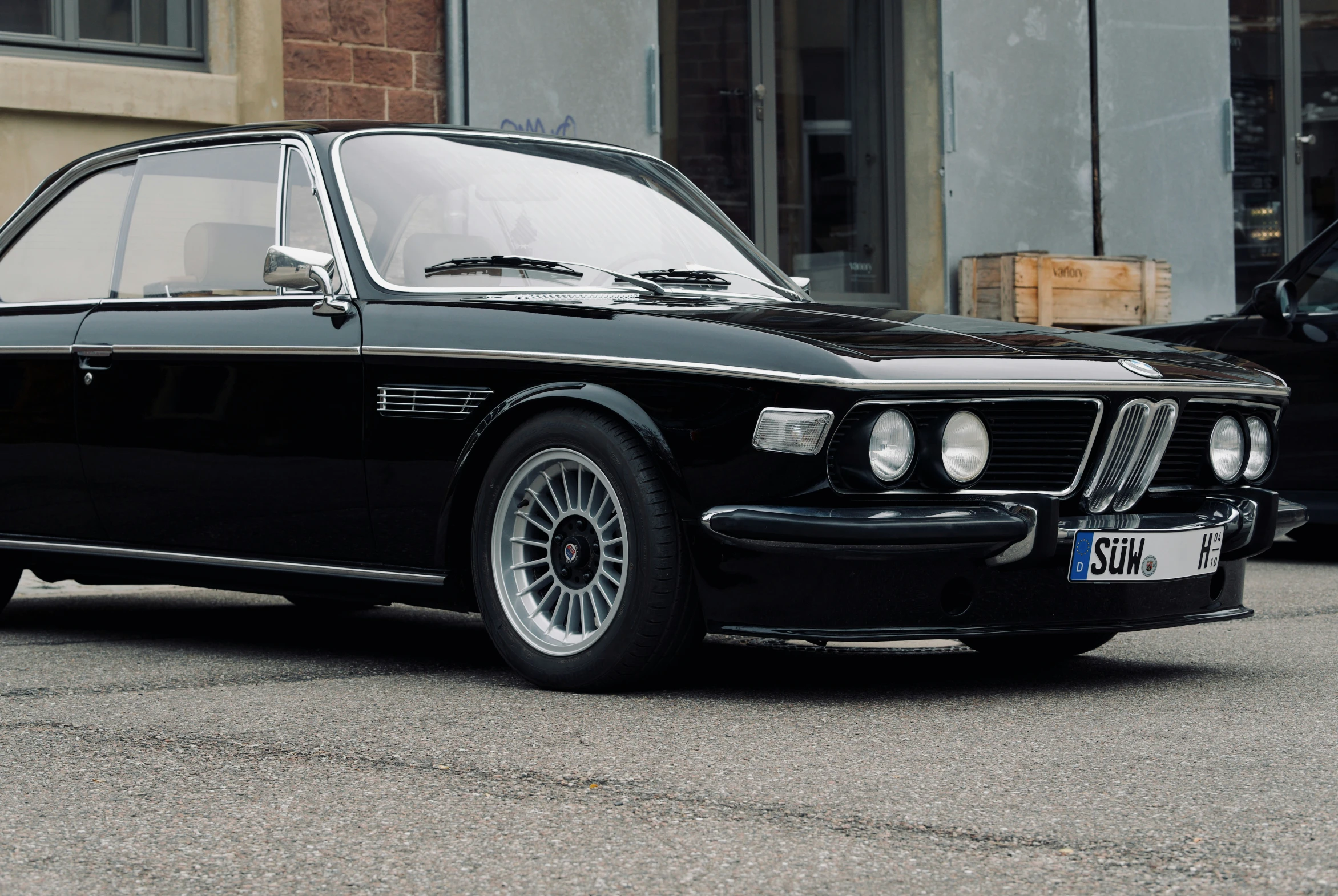 a black bmw coupe is parked on the pavement