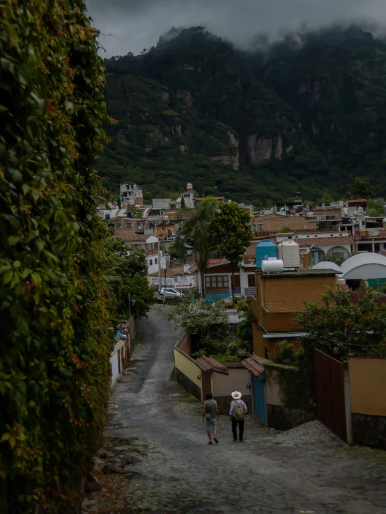 two people are walking down the road in front of some houses