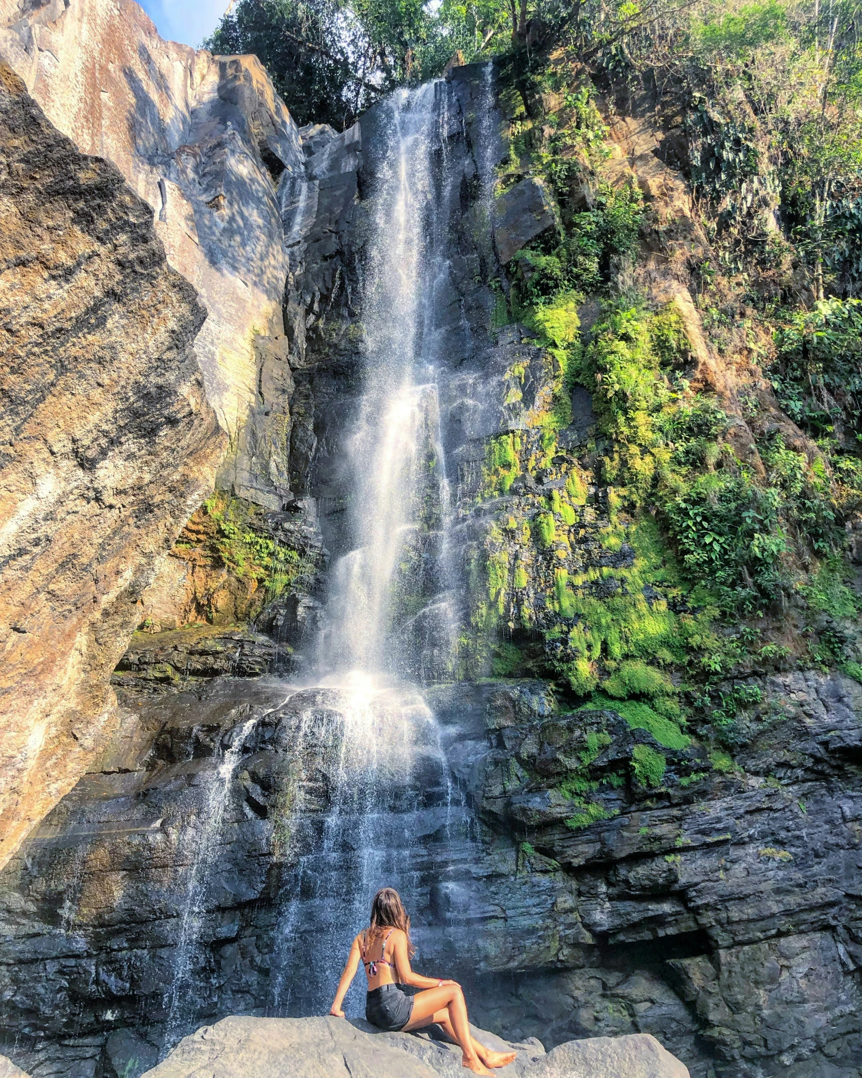 girl sitting on the rocks near the waterfall