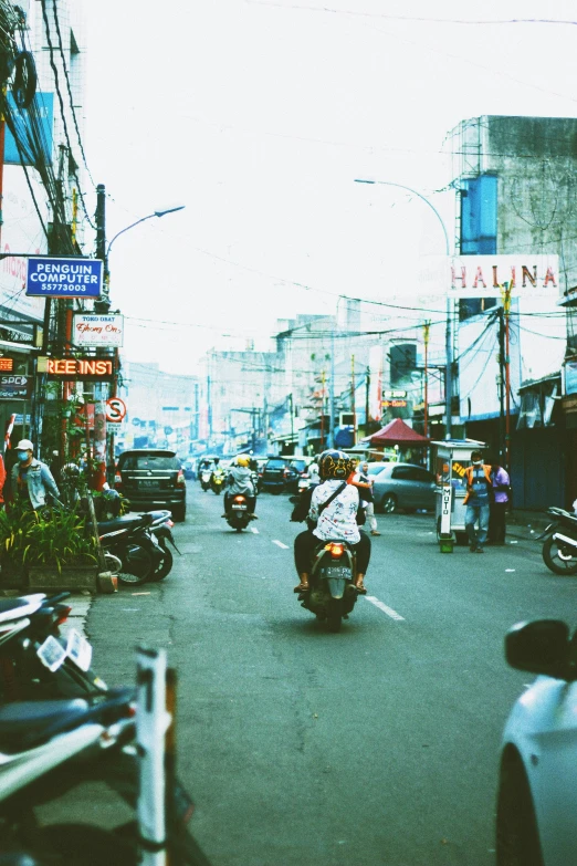 a busy street has several motorcycles, people and various stores