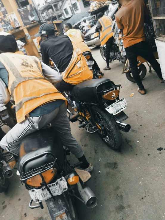 two men riding on the back of motorcycles on the street