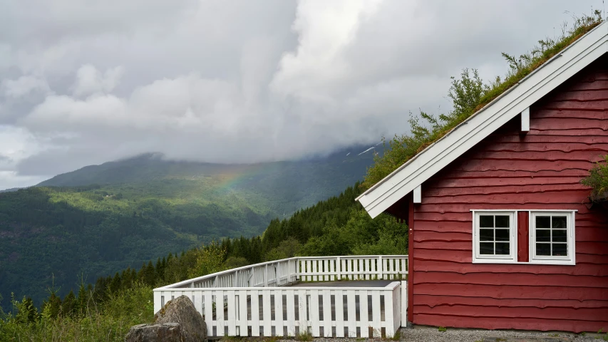 a red building and white railing near mountains