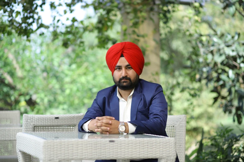 an indian man wearing a red turban sitting in front of a table