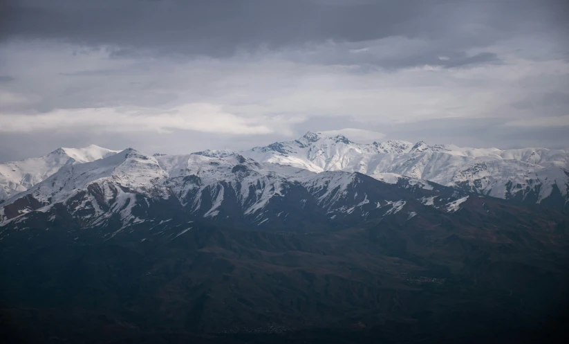 snow - covered mountains covered in clouds under dark skies