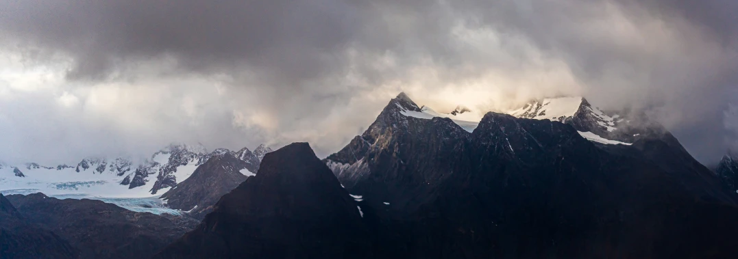 a group of mountain peaks with clouds in the sky