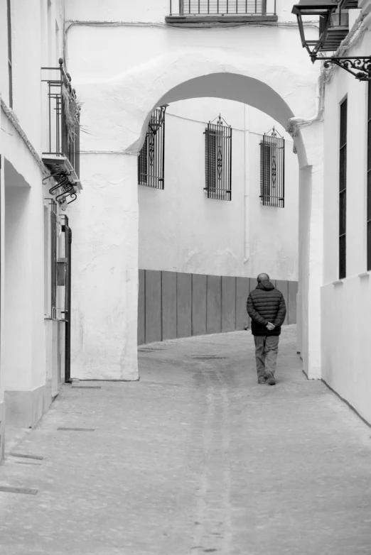 black and white po of man walking through a narrow alleyway