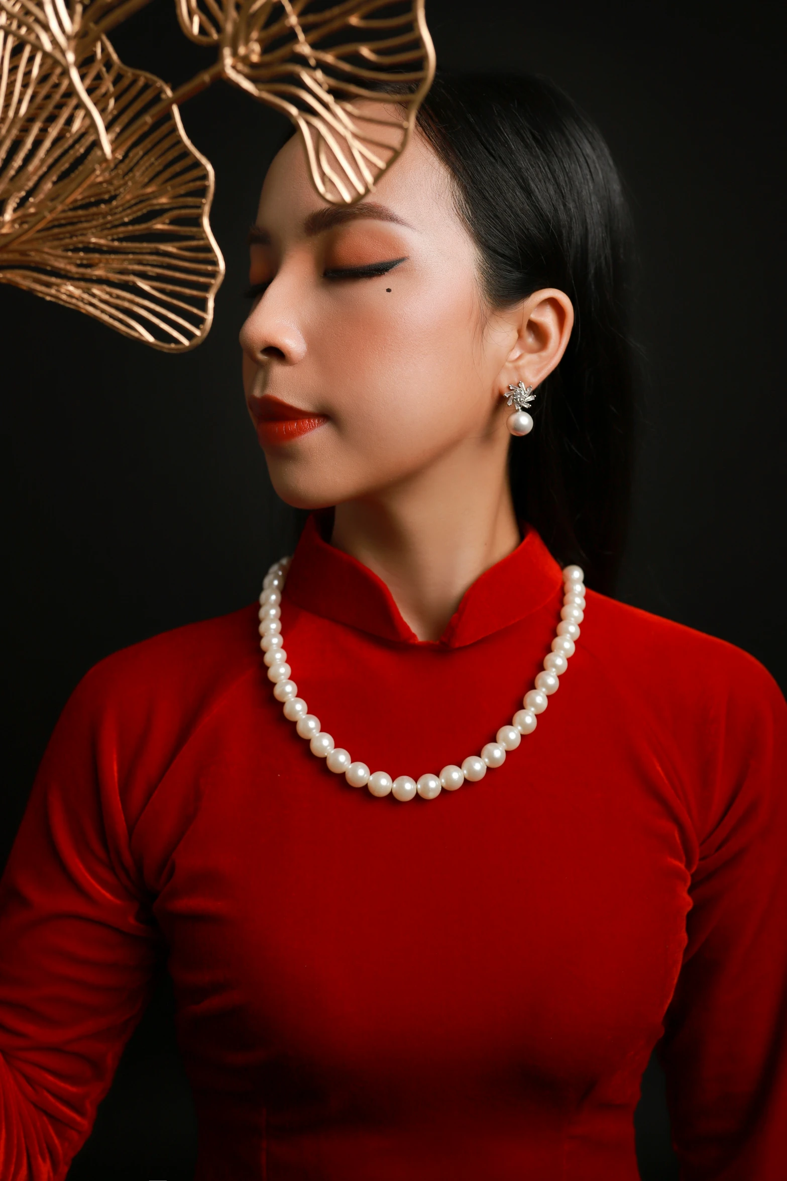 asian woman dressed in a red shirt with pearls