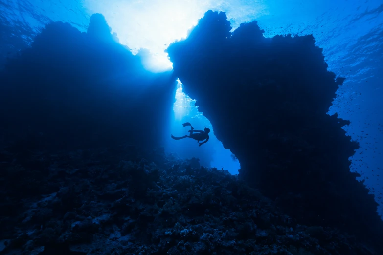 the underwater view from underneath a ship shows a diver and their shadow