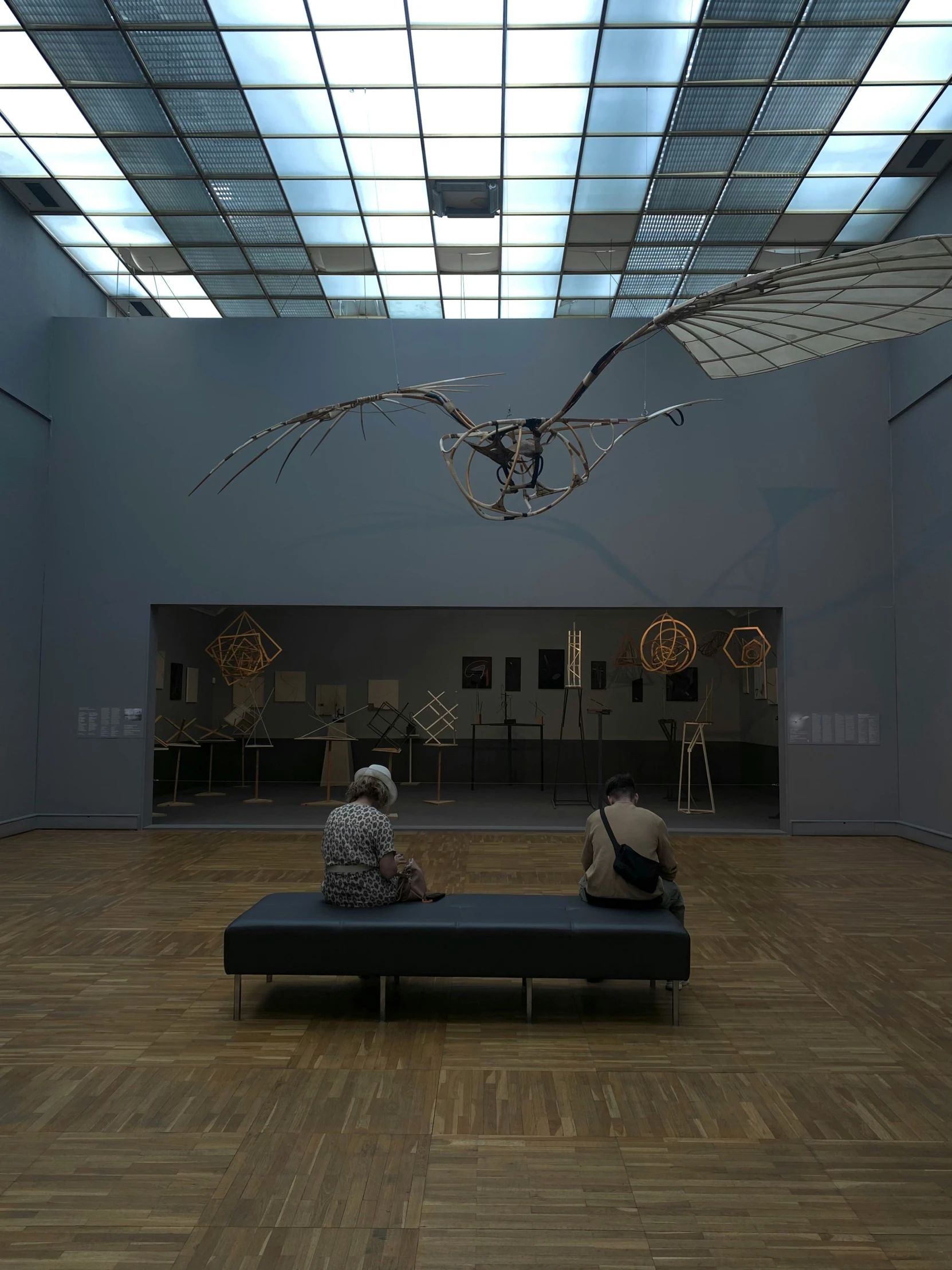 two people sitting on a bench looking at a sculpture