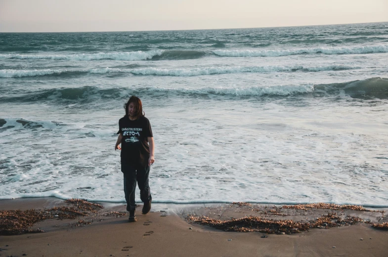 a girl in a wet suit standing on a beach near the ocean