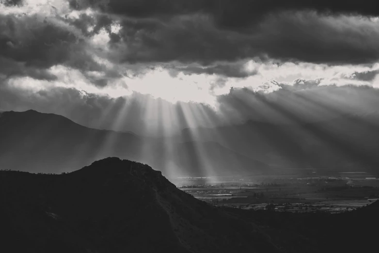 clouds loom over a mountain with the sun shining through the clouds