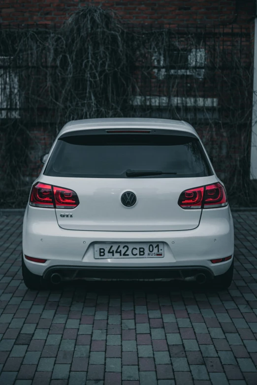 white car parked on a brick surface next to a building