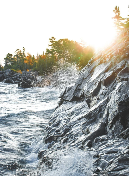 the sun shines over rocky shore on a clear day