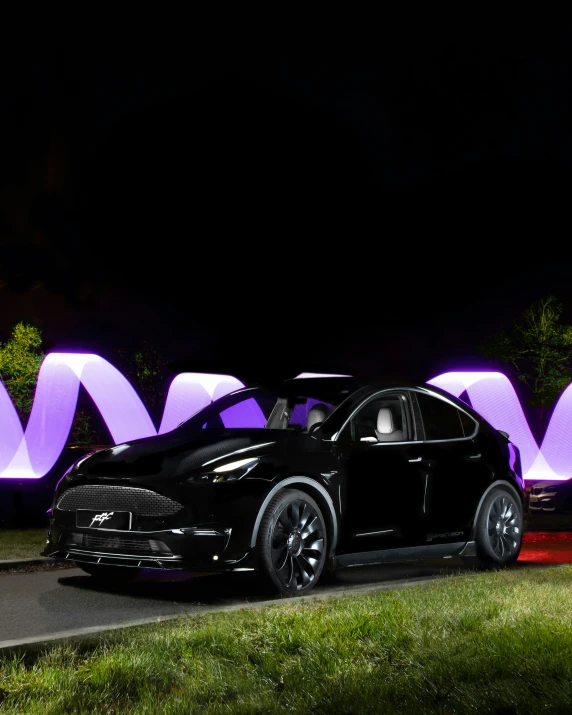 a black tesla car is parked in front of a letter m