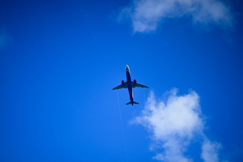 a blue airplane flying in the air on a clear day