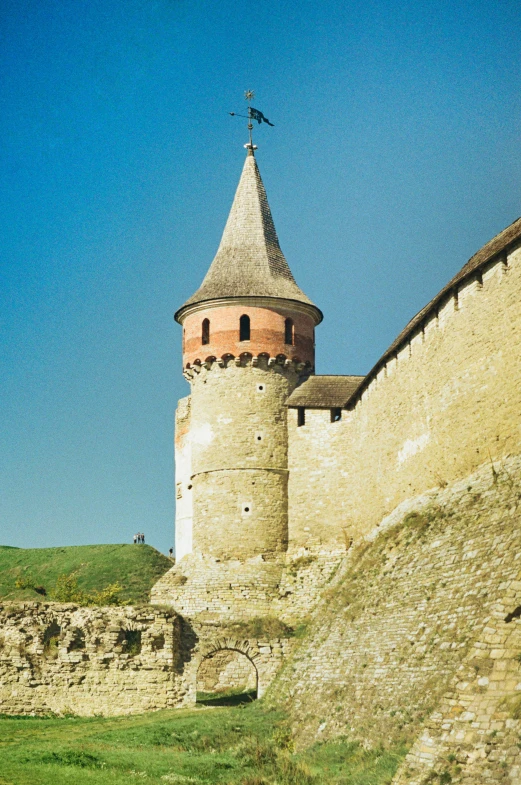 the tall brick building with a tower is in the countryside