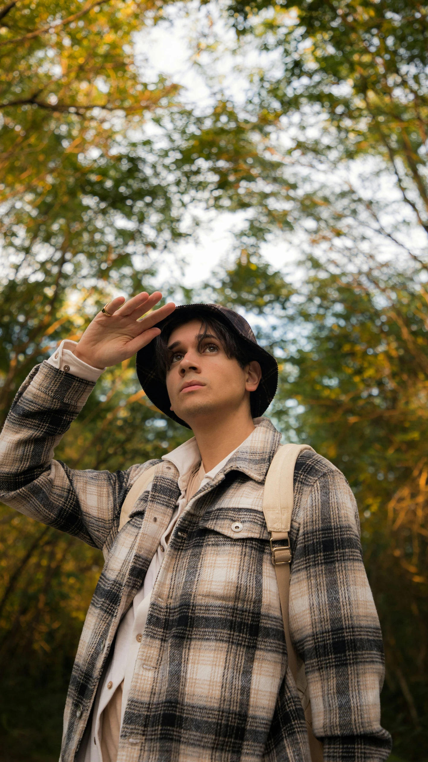 man in plaid jacket and black hat looking up