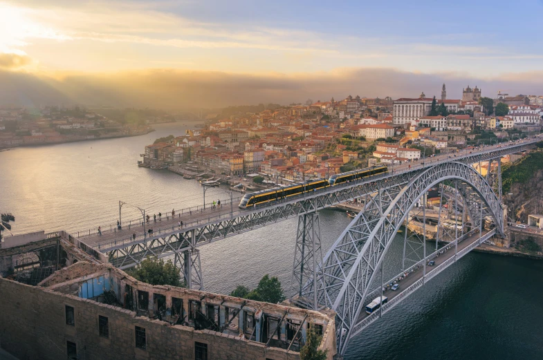 the bridges over a town's river with a yellow train going across