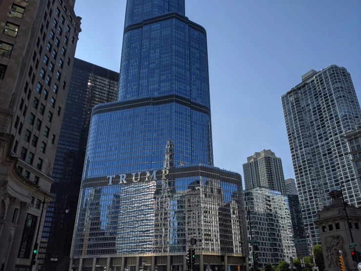 the top of a skyscr is reflecting in the windows of other buildings