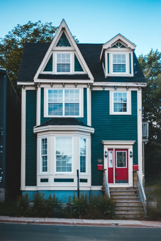 two - story blue house with red front door and stairs