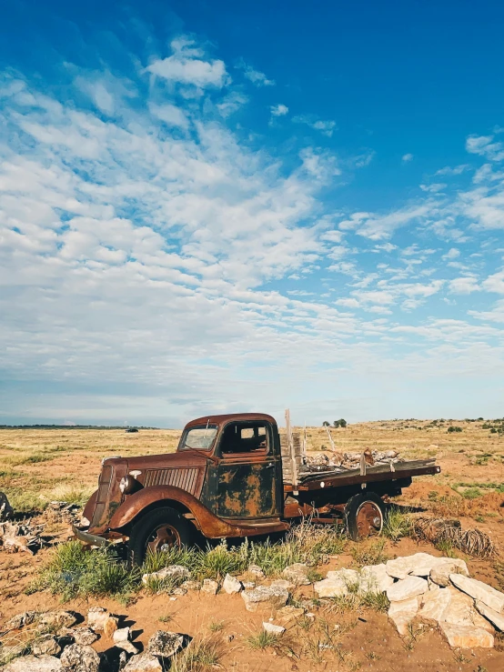 an old rusted truck sitting on a dirt field