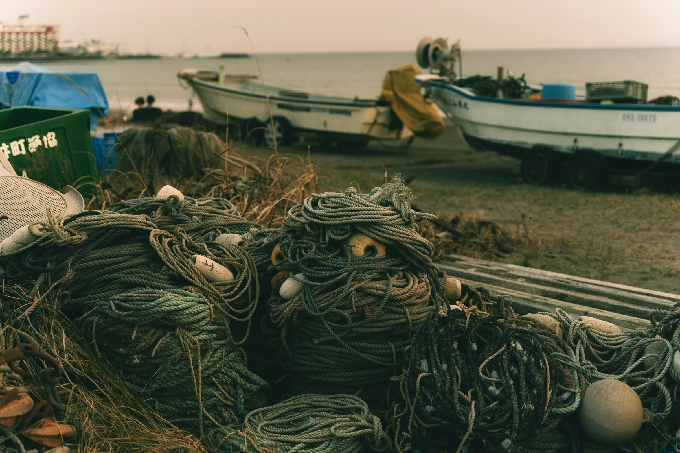 a pile of rope on the beach with a small boat in the background