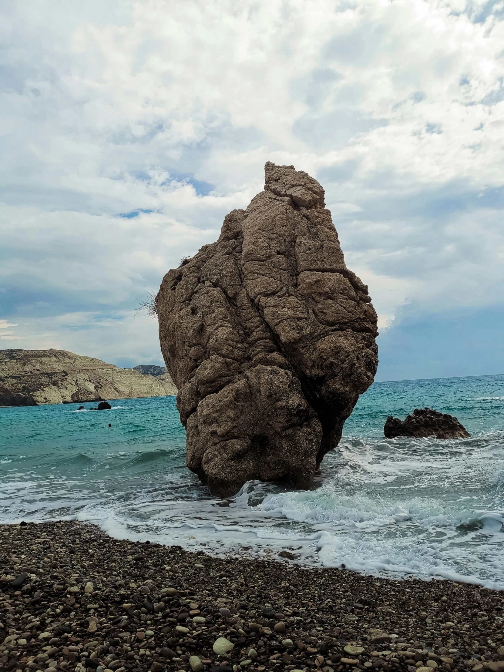 large rock on the edge of a beach near the ocean