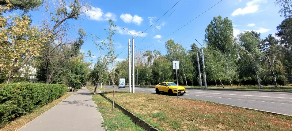 a sidewalk with several wires over it leading to a yellow car