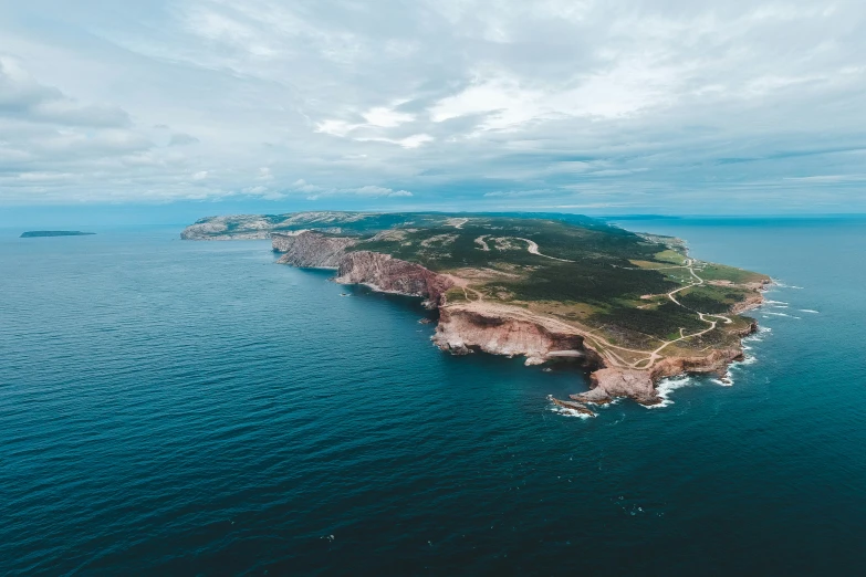 an aerial view of a island on the ocean with many boats sailing