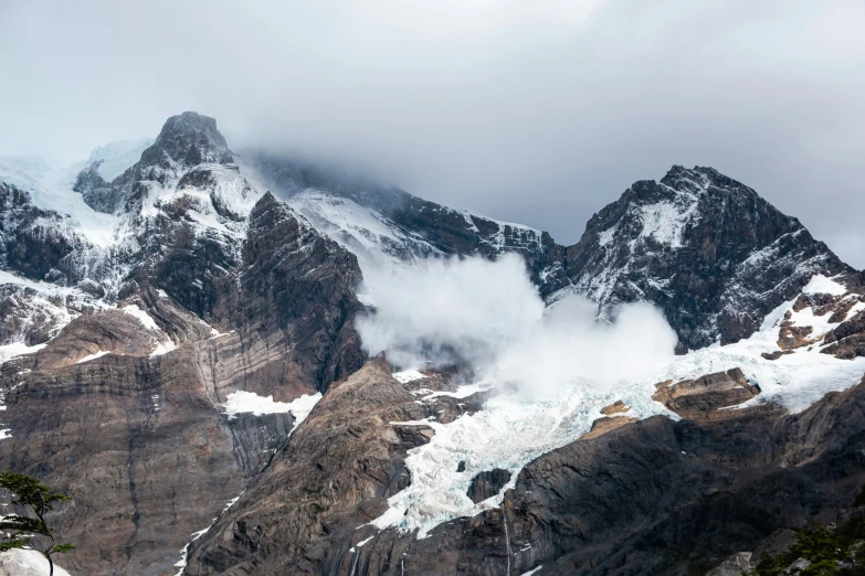 a snow covered mountain range under clouds in the mountains