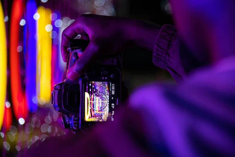 a man taking a po on his phone in front of colorful lights