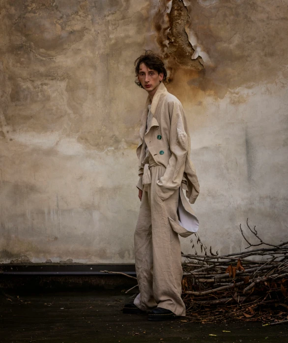 a young man is standing next to a wall